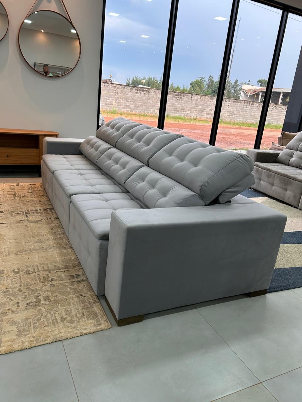 Sofá cinza no showroom da Dubai, com janelas amplas e outros modelos ao fundo