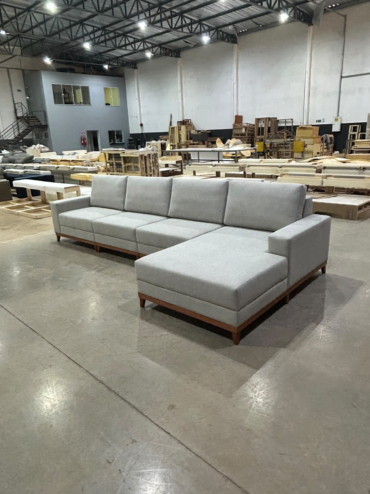 Sofá living cinza-claro com chaise e base de madeira